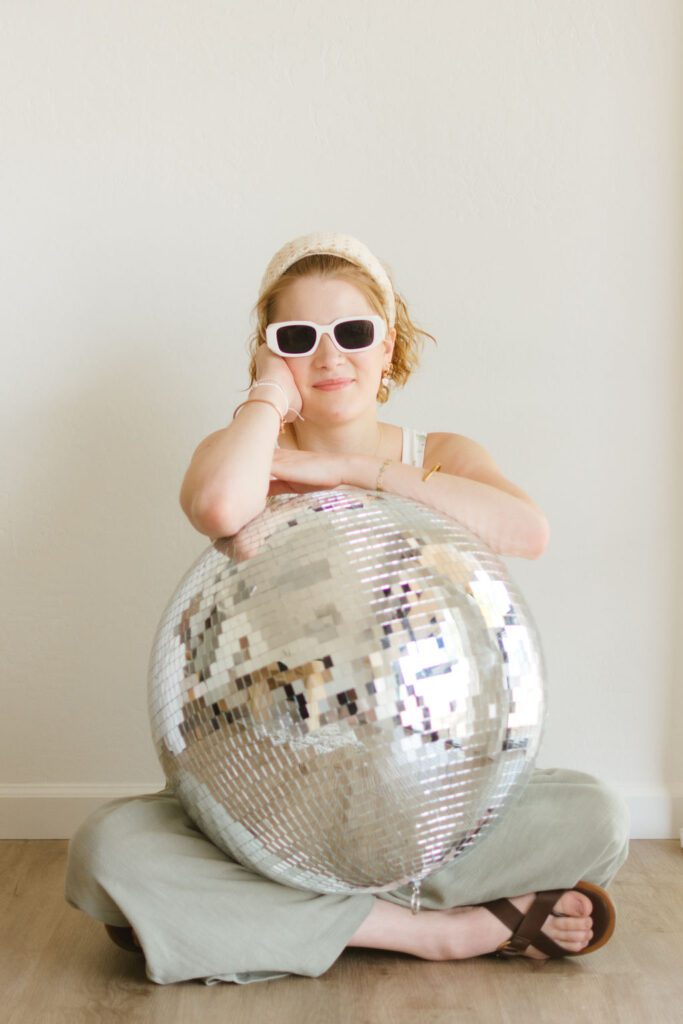 virtual business coach propped up on a disco ball looking at the camera
